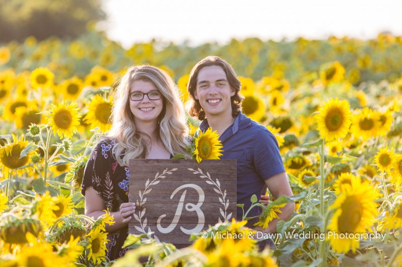 Picture of engaged couple holding sing with their letter on it.